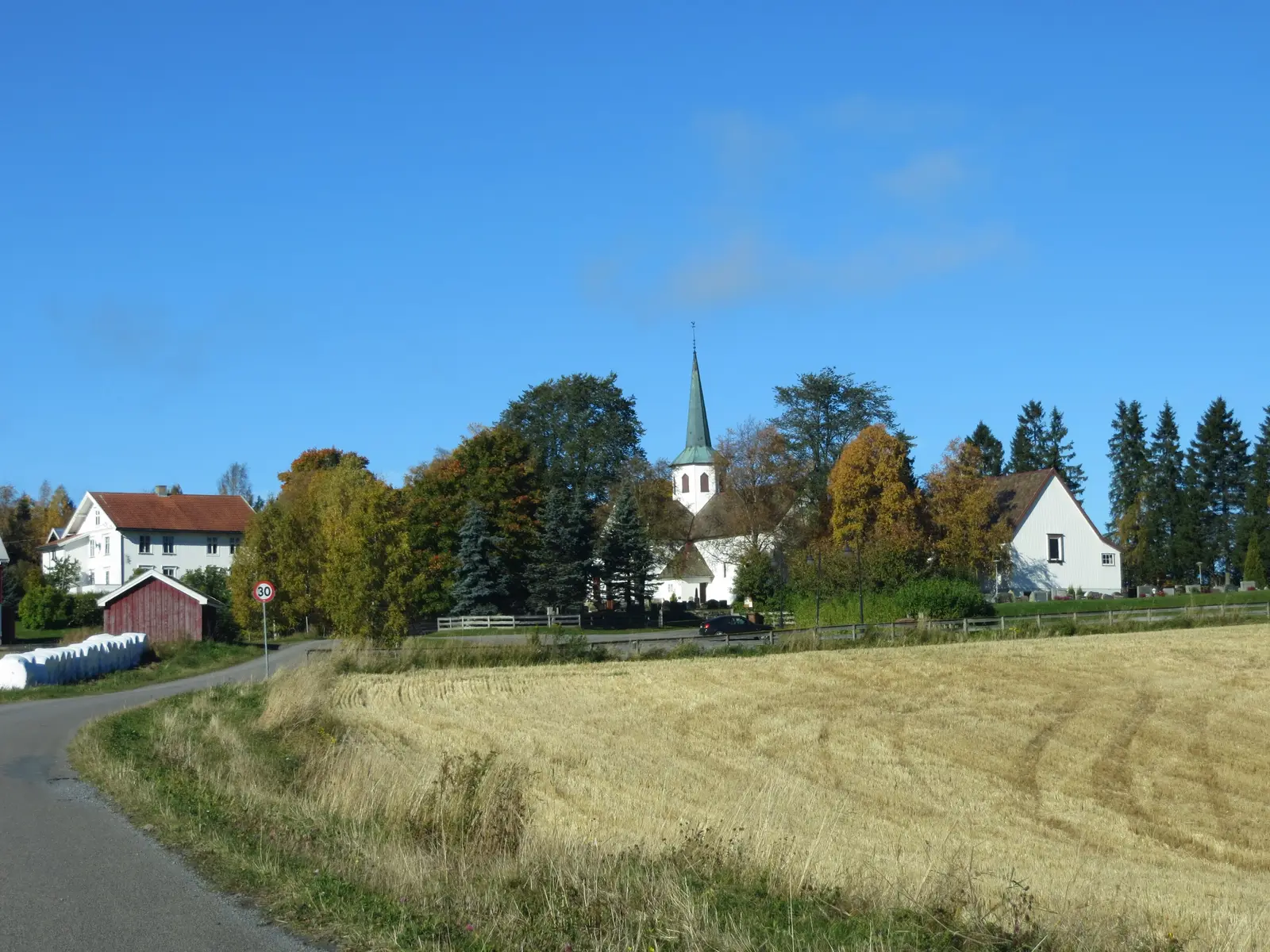 Lunner kirke bak et kornåker en høstdag
